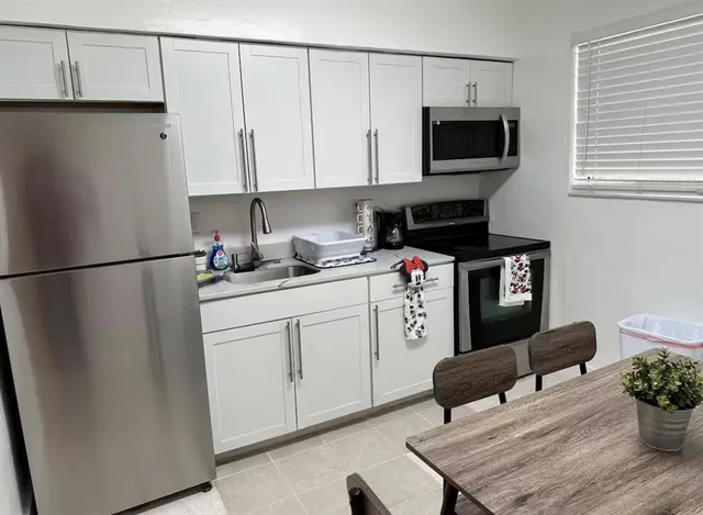 a kitchen with stainless steel appliances white cabinets sink and a refrigerator