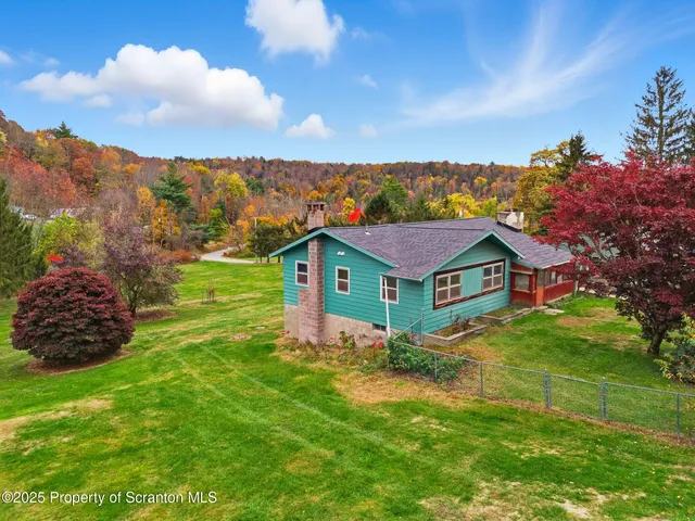 a view of a house with a big yard and large trees