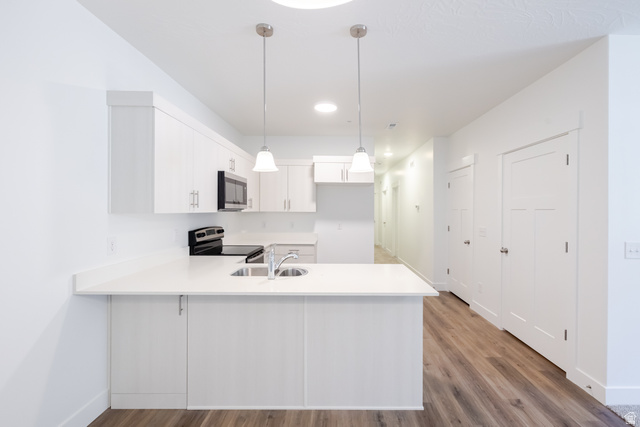 4727 South 690th West, Unit W203 Mapleton, UT 84664 - Photo 14 of 16 Modern kitchen featuring white cabinetry, a large kitchen island with an integrated sink, and stainless steel appliances