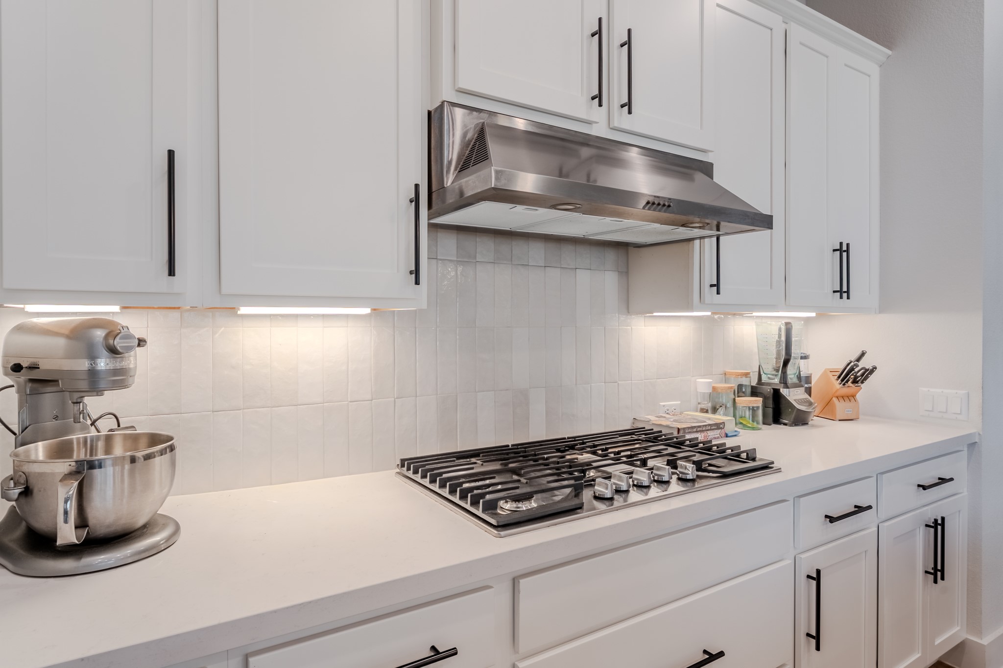 8109 Edmondson Bend Austin, TX 78744 - Photo 30 of 38 White cabinetry and countertops complement the modern gas cooktop and stainless steel range hood.