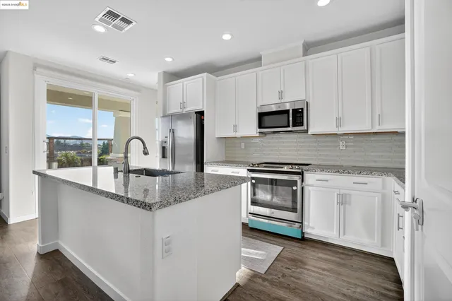a kitchen with stainless steel appliances granite countertop a stove a sink and a microwave