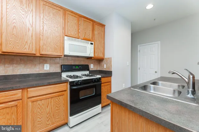 a kitchen with granite countertop a sink stove and cabinets