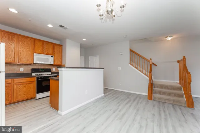 a view of kitchen with stainless steel appliances wooden floor and cabinets