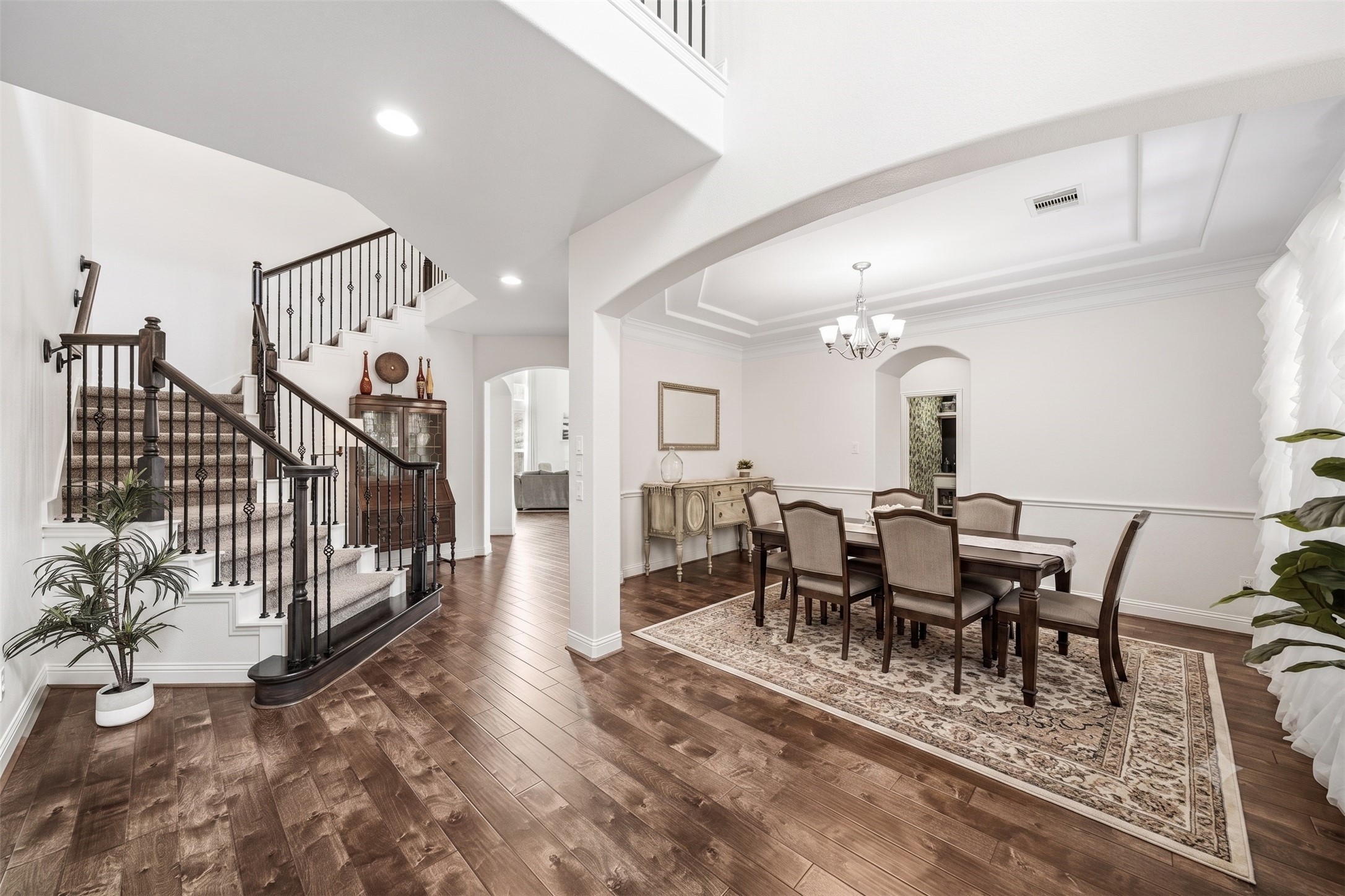 17610 Strackfield Lane Tomball, TX 77377 - Photo 5 of 50 The formal dining room exudes classic elegance with double crown molding and has a beautifully appointed chandelier as its centerpiece. The arched doorway leads to the pantry and Butler's pantry.The wrought iron staircase leads to the upstairs. This photo has been virtually staged.