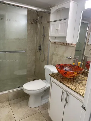 a bathroom with a granite countertop sink a toilet and a shower