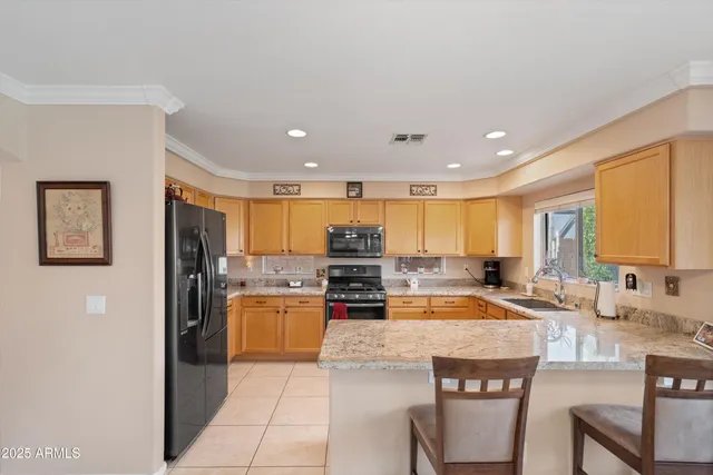 a kitchen with stainless steel appliances granite countertop a stove top oven a sink a refrigerator white cabinets and couches with wooden floor