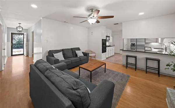 a living room with furniture kitchen view and a wooden floor