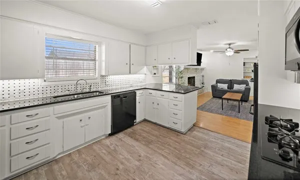a kitchen with granite countertop a sink cabinets stainless steel appliances and a window