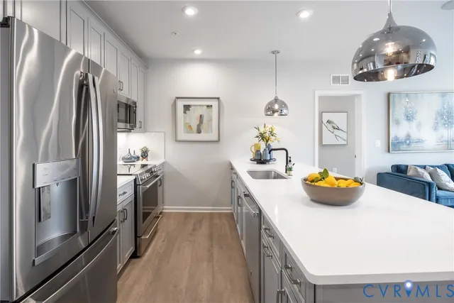 a kitchen with stainless steel appliances a chandelier a refrigerator and a sink