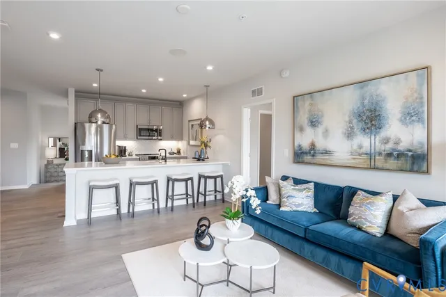 a living room with stainless steel appliances furniture and a view of kitchen