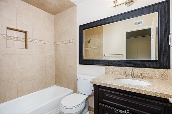 a bathroom with a granite countertop sink toilet a mirror and shower