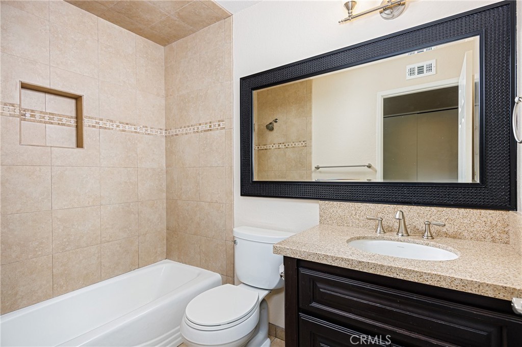 25885 Trabuco Road, Unit 206 Lake Forest, CA 92630 - Photo 18 of 40 a bathroom with a granite countertop sink toilet a mirror and shower