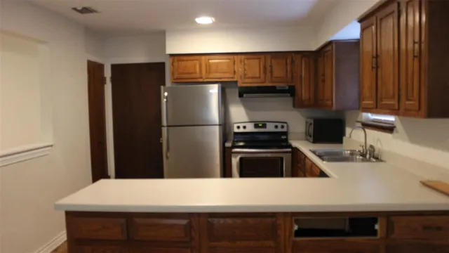 a kitchen that has a refrigerator a stove and a sink with wooden cabinets