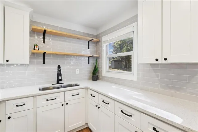 a kitchen with white cabinets and window