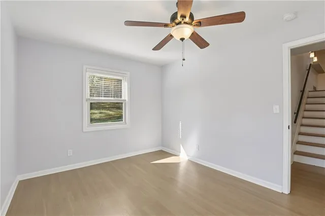 an empty room with wooden floor fan and windows