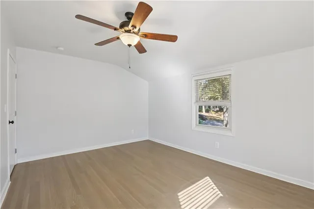 an empty room with a window and ceiling fan