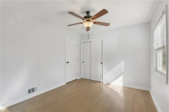 an empty room with wooden floor and ceiling fan