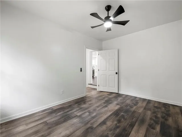 an empty room with wooden floor and ceiling fan