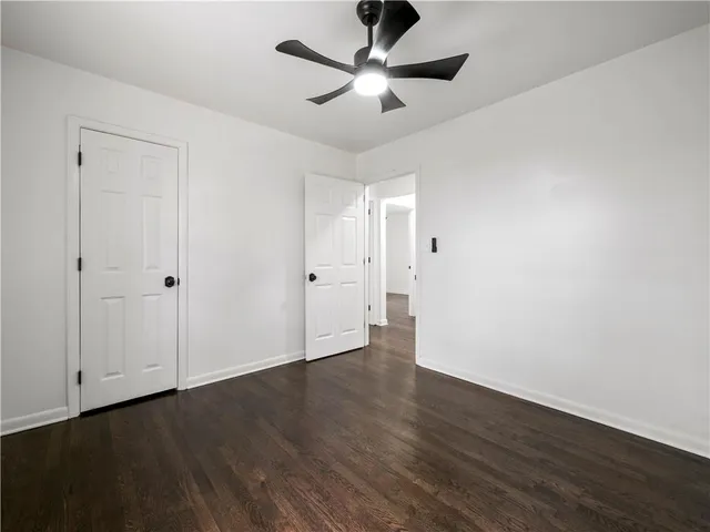 an empty room with wooden floor ceiling fan and windows