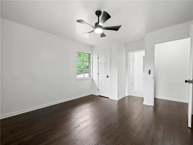 an empty room with wooden floor ceiling fan and window