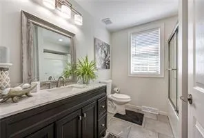 a bathroom with a granite countertop sink toilet a large mirror and a window