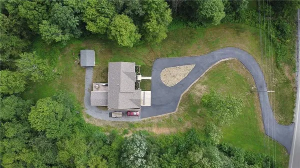 an aerial view of a house with swimming pool and trees all around