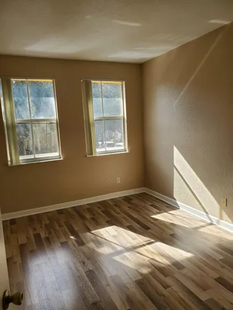 a view of an empty room with wooden floor and a window