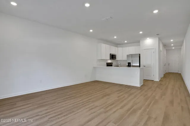 a view of kitchen with kitchen island wooden floor center island and stainless steel appliances