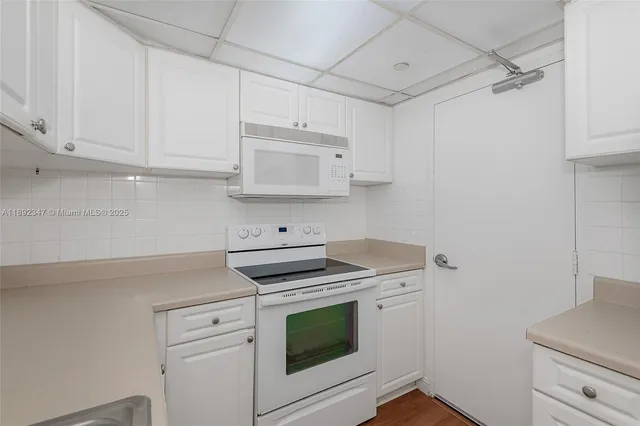 a kitchen with white cabinets and white appliances