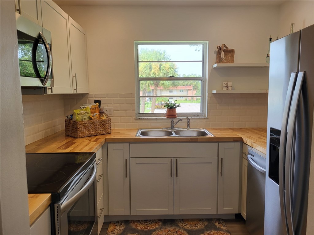 a kitchen with a sink cabinets stainless steel appliances and a window