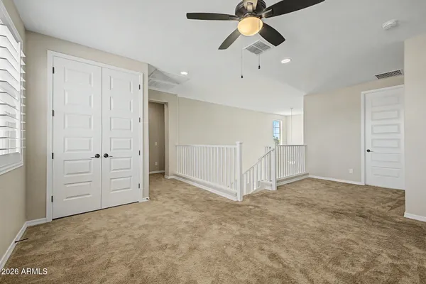 an empty room with closet and ceiling fan