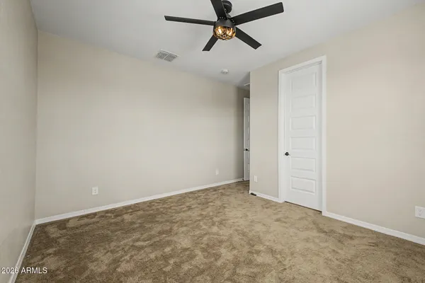 an empty room with chandelier fan and windows
