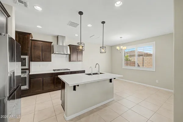 a kitchen with stainless steel appliances granite countertop a sink a stove a refrigerator and island with wooden floor