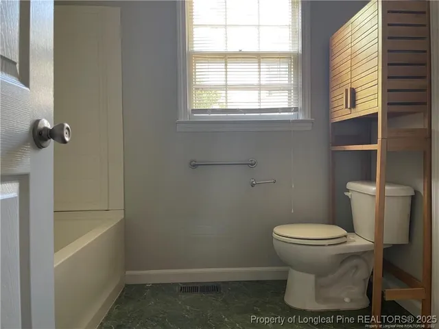 a white toilet sitting next to a bath tub
