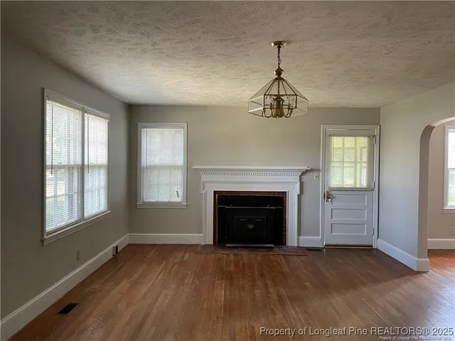 an empty room with windows a fireplace and wooden floor