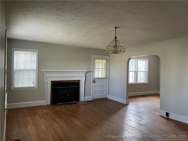wooden floor fireplace and windows in an empty room