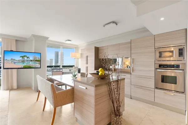 a kitchen with stainless steel appliances kitchen island granite countertop a stove a refrigerator a dining table and chairs with wooden floor