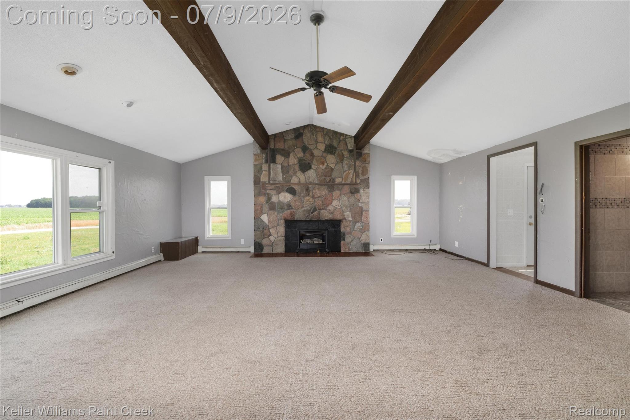 28780 School Section Road Richmond, MI 48062 - Photo 28 of 50 Spacious living area featuring a vaulted ceiling with exposed wood beams, a stone-faced fireplace, and a ceiling fan