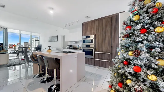 a kitchen with stainless steel appliances granite countertop a dining table chairs and a refrigerator