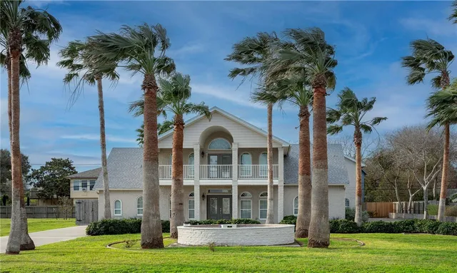 a front view of a house with a yard and palm trees