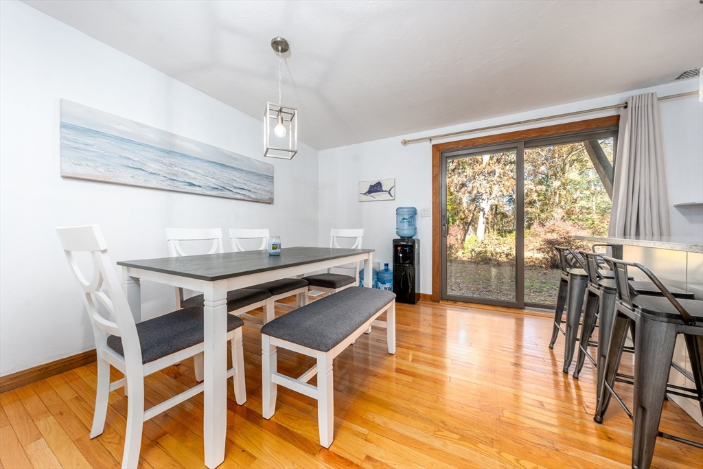 195 Falmouth Road, Unit 9D Mashpee, MA 02649 - Photo 27 of 29 a dining room with wooden floor a chandelier a wooden table and chairs