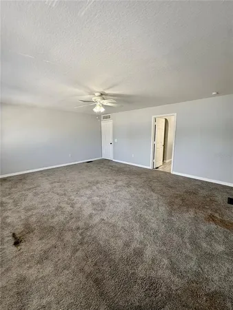 an empty room with windows and fan