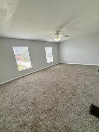 an empty room with windows and ceiling fan view