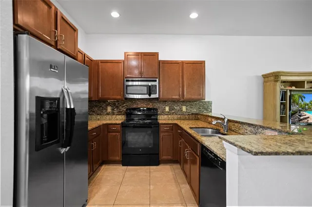 a kitchen with stainless steel appliances granite countertop a sink and a refrigerator