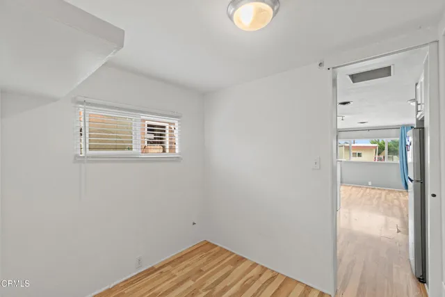 a view of a hallway with wooden floor and a bathroom