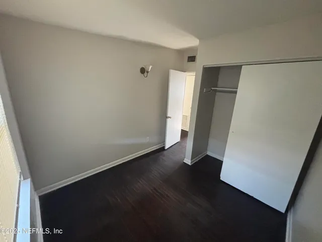 an empty room with wooden floor and closet