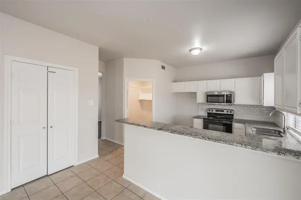 a kitchen with granite countertop a refrigerator and a sink