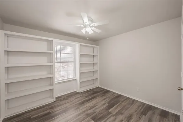 an empty room with wooden floor and fan