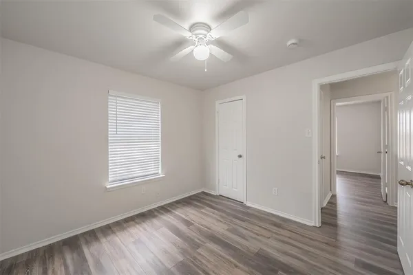 an empty room with wooden floor fan and windows