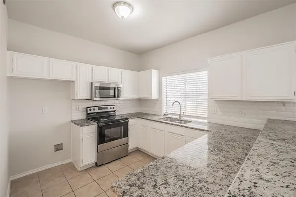 a kitchen with stainless steel appliances granite countertop a stove a sink and a microwave